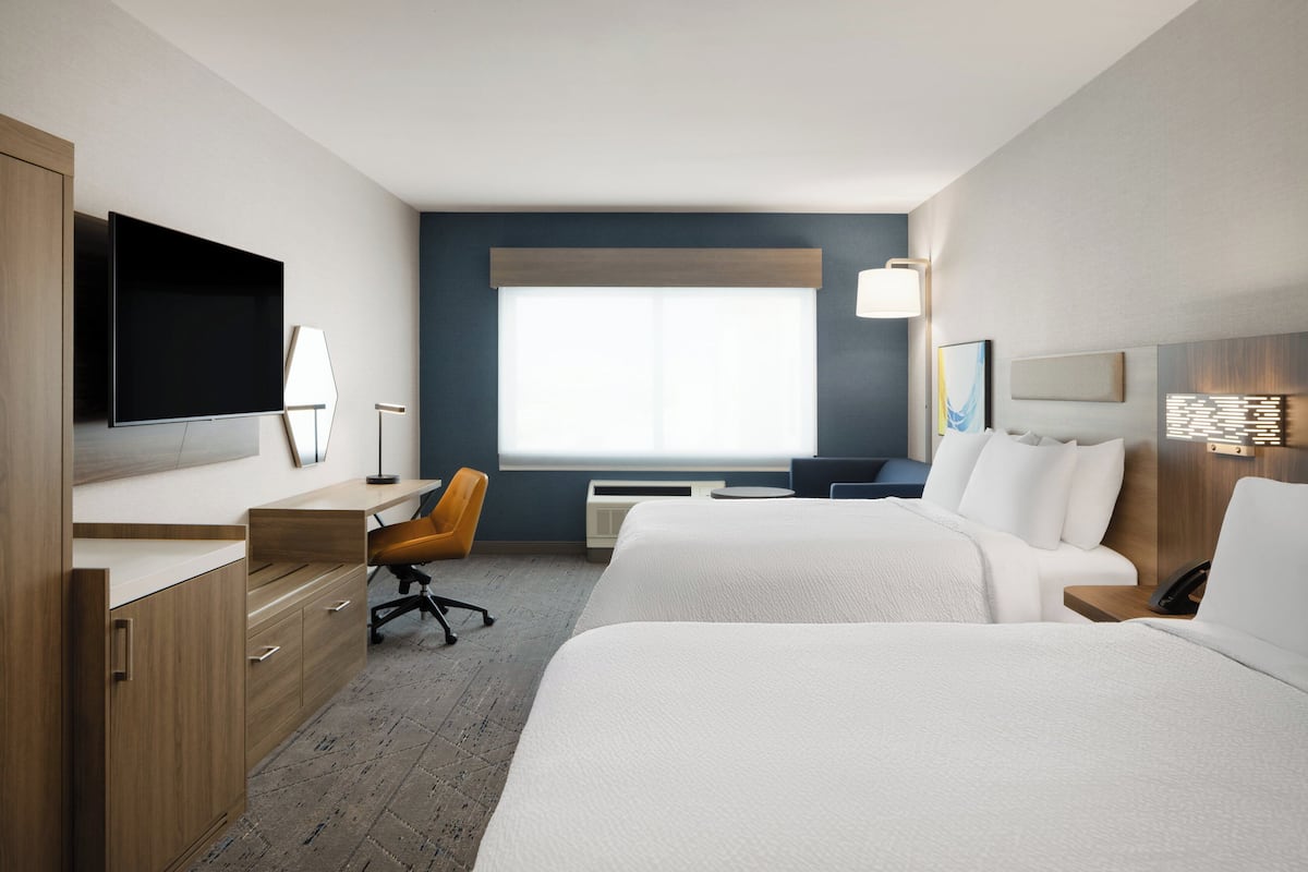 Une chambre d’hôtel avec un lit, un bureau, une chaise, une télévision et une fenêtre.