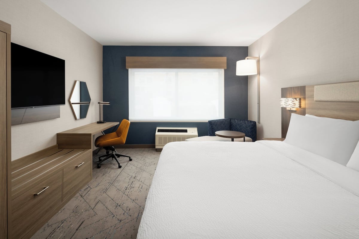 Une chambre d’hôtel équipée d’un lit, d’un bureau, d’une chaise, d’une télévision, d’une fenêtre et d’une lampe.