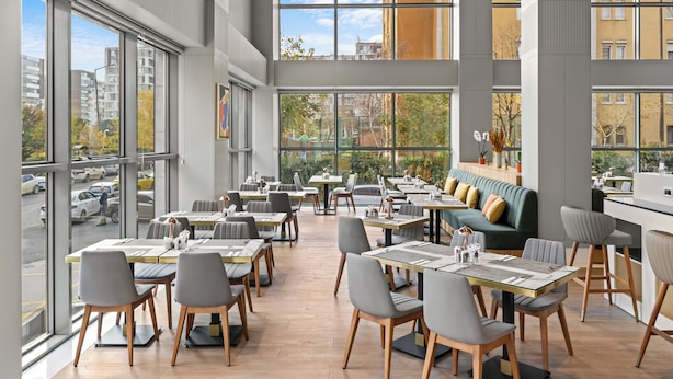 A modern restaurant with large windows, wooden flooring, and a mix of tables and seating areas. - Holiday Inn Istanbul - Beylikduzu by IHG (Istanbul)