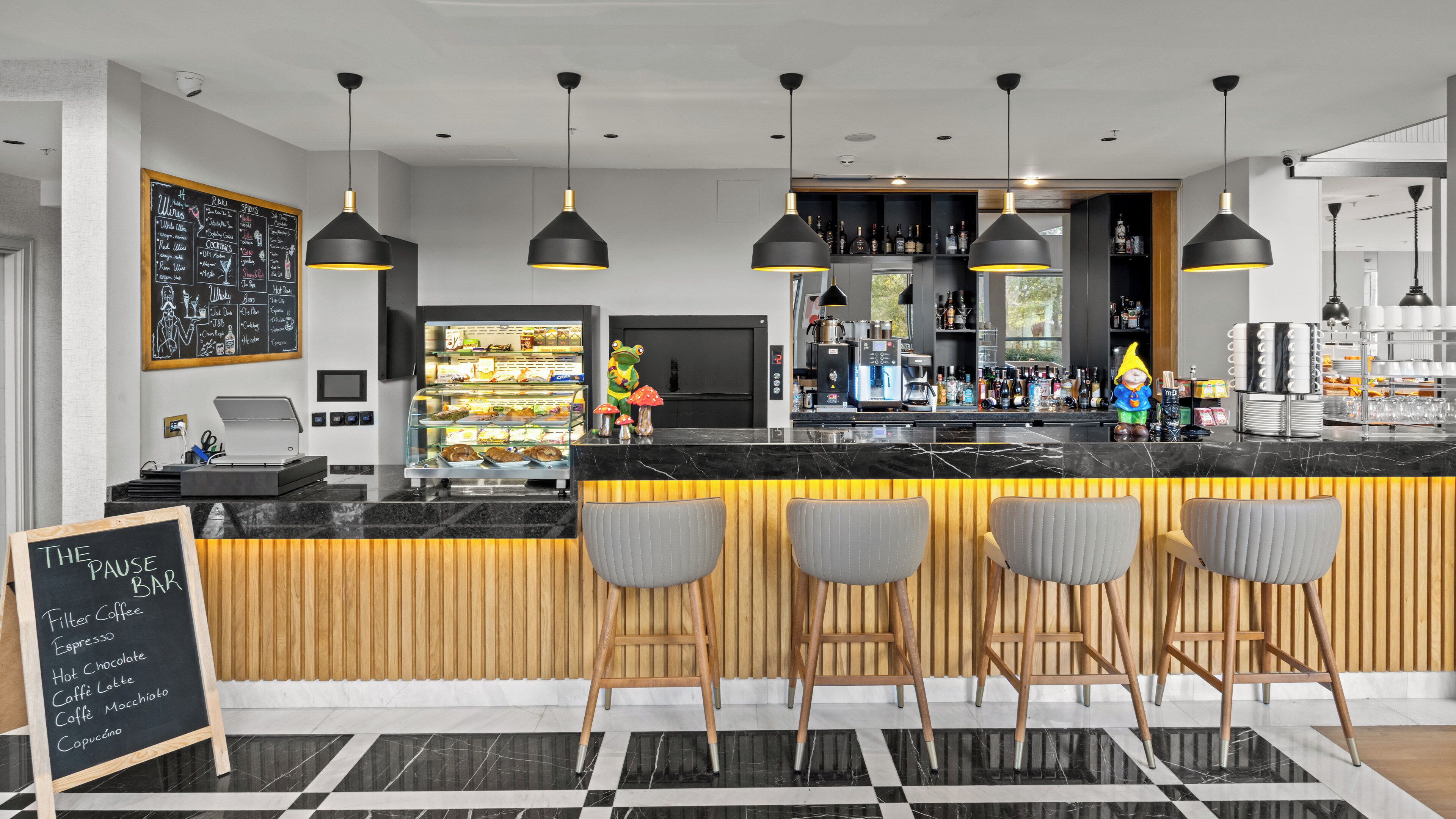 A modern bar with a marble countertop, black pendant lights, and wooden accents.