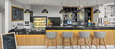 A modern bar with a marble countertop, black pendant lights, and wooden accents.