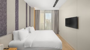 A modern hotel room with a large bed, a flat-screen TV mounted on the wall, and a window with sheer curtains. - Holiday Inn Istanbul - Beylikduzu by IHG (Istanbul)