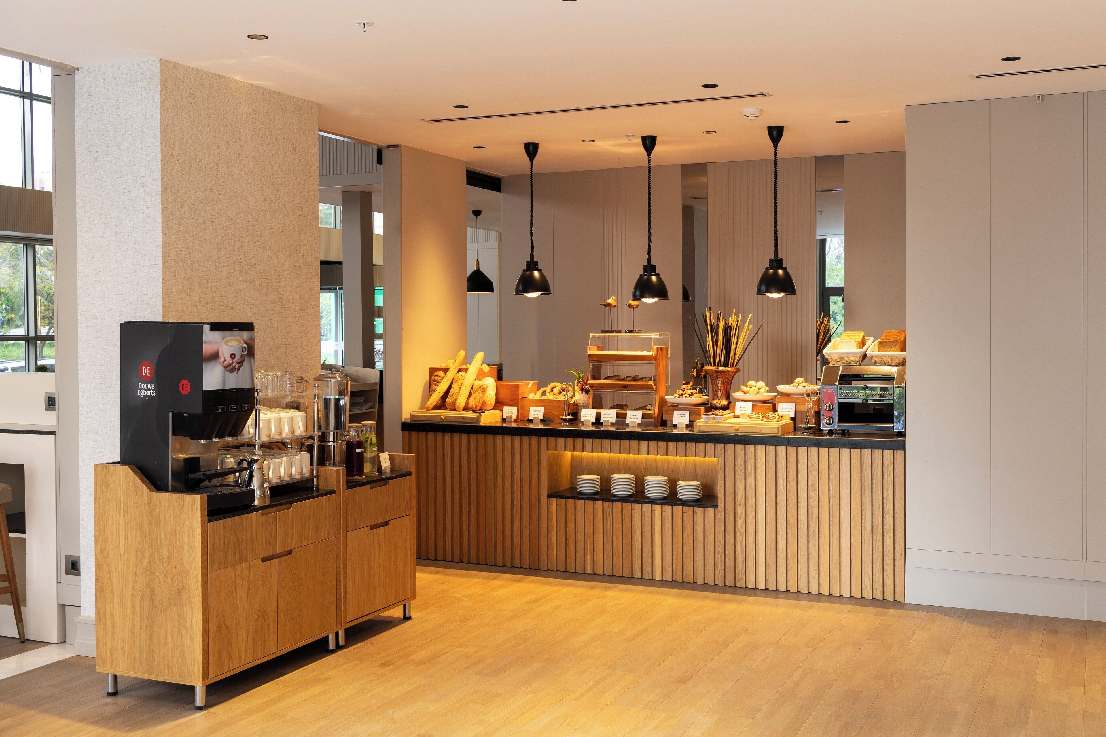 A modern kitchen with a coffee station, wooden cabinets, and pendant lighting.