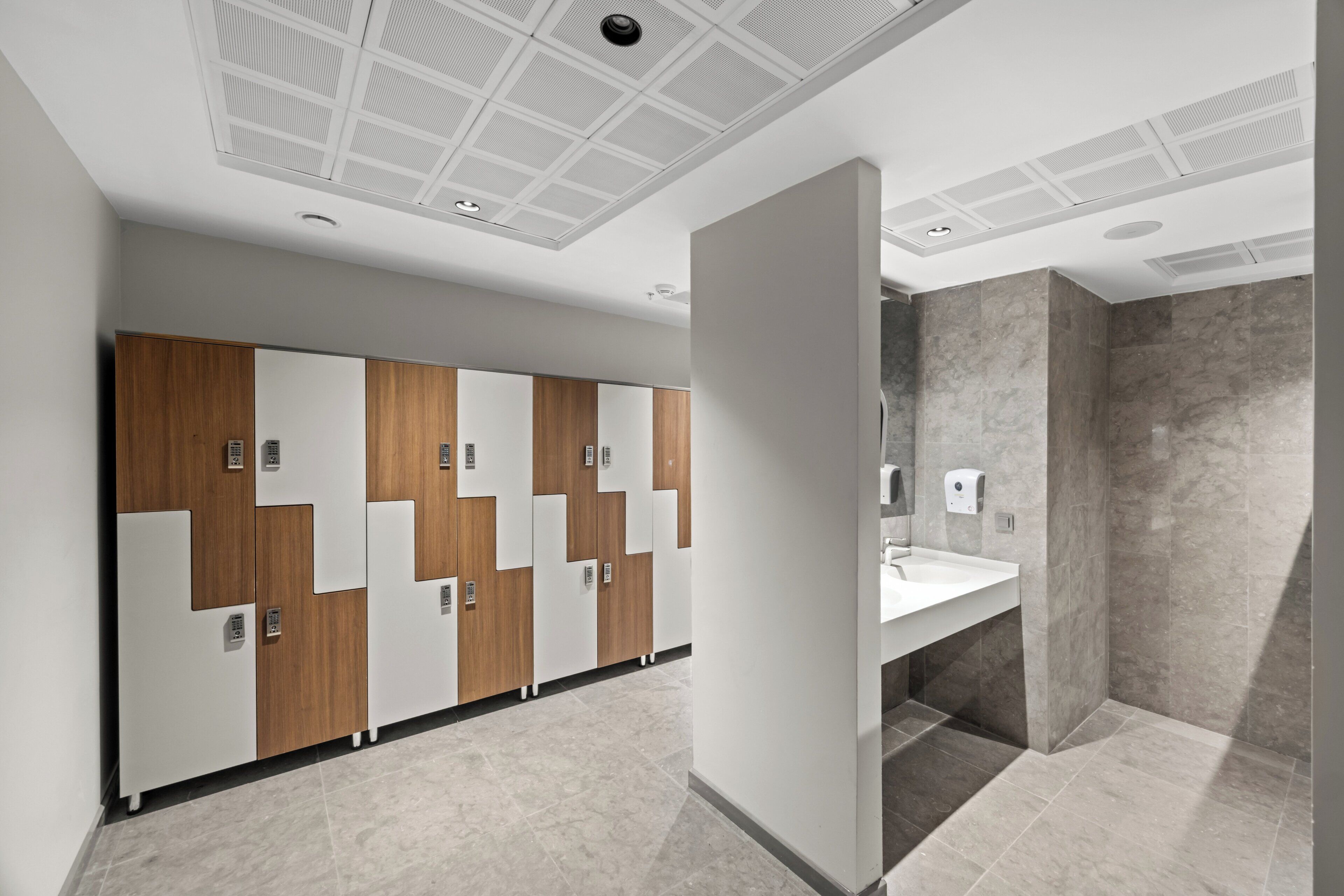 Un baño moderno con una fila de casilleros, un lavabo y un espejo.