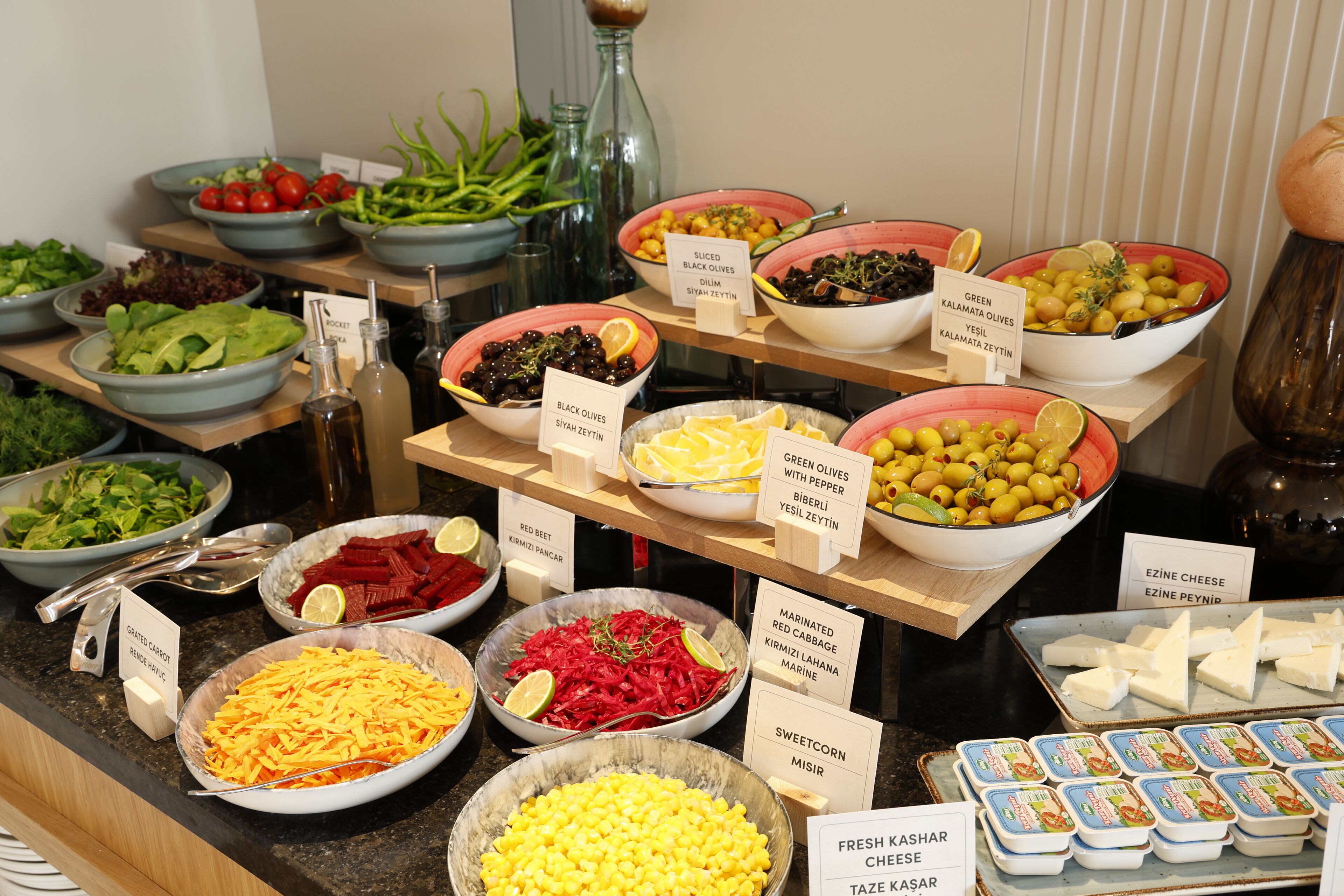 Een buffet met diverse gerechten, waaronder salades, kazen en olijven.
