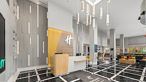 A modern hotel lobby with a reception desk, check-in counters, and a seating area with a black and white checkered floor. - Holiday Inn Istanbul - Beylikduzu by IHG (Istanbul)