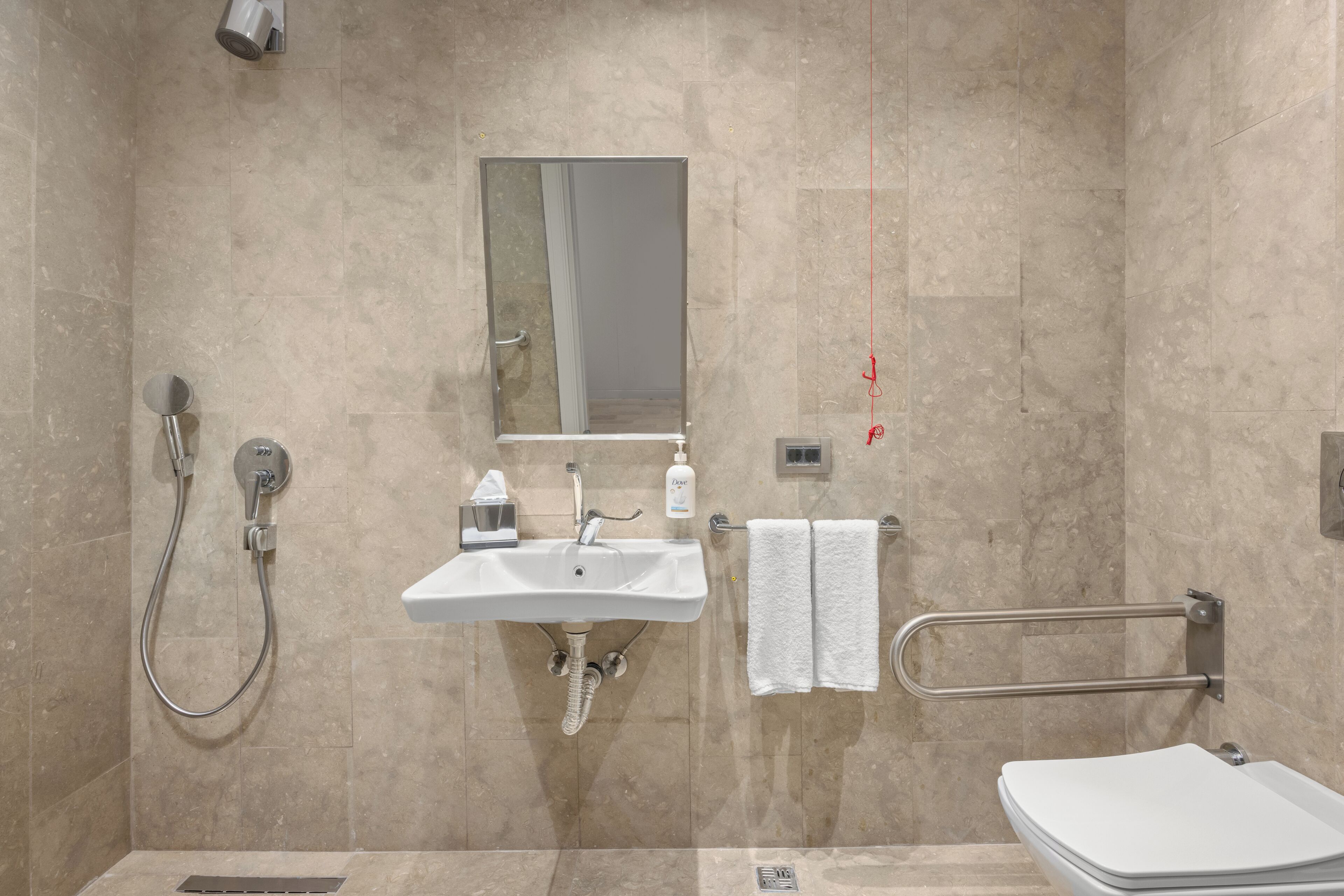 A modern bathroom with a sink, mirror, towel rack, and shower.