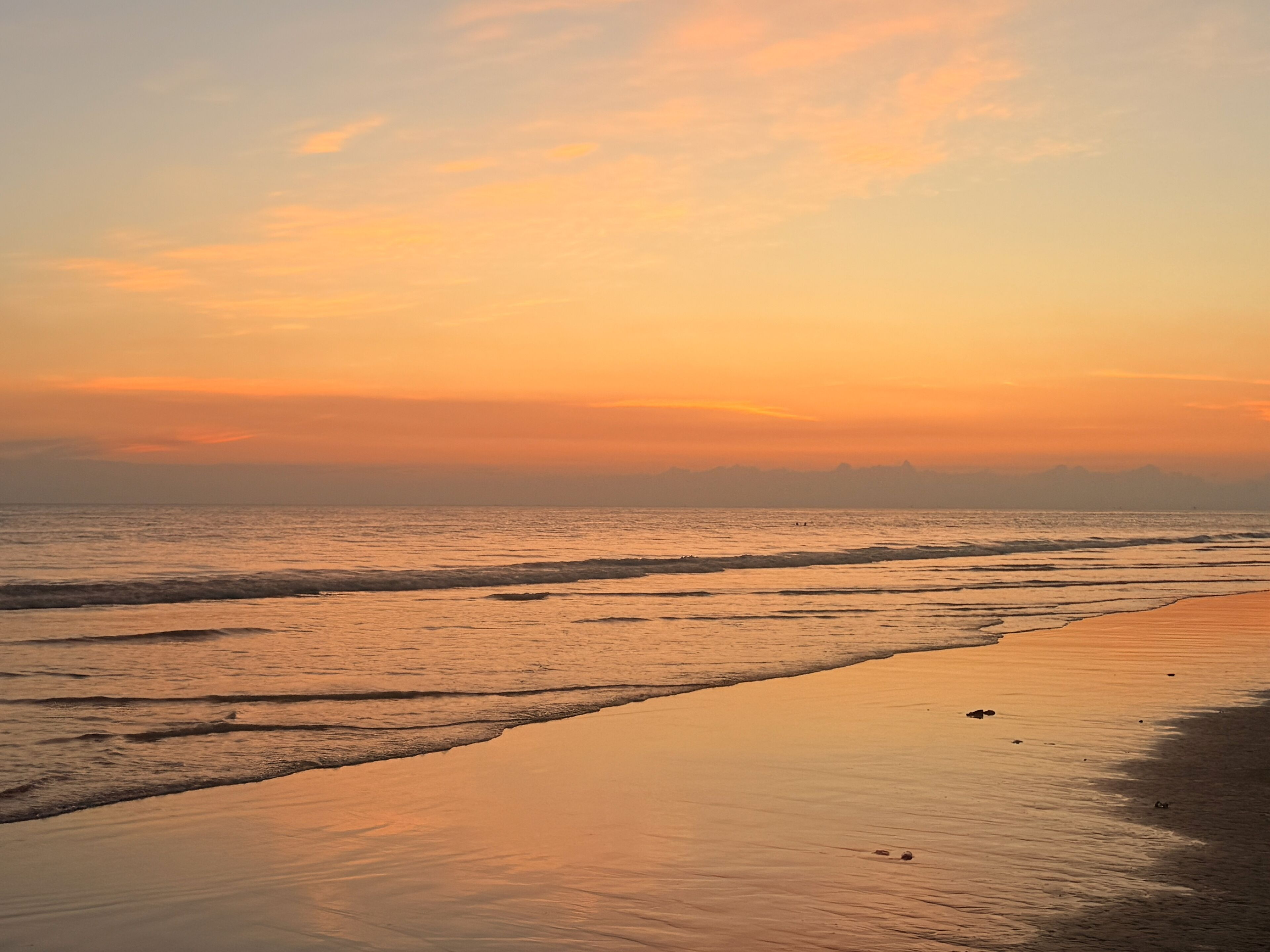 A beach with waves at sunset.