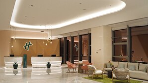 A modern hotel lobby with a reception desk, seating area, and a sofa.