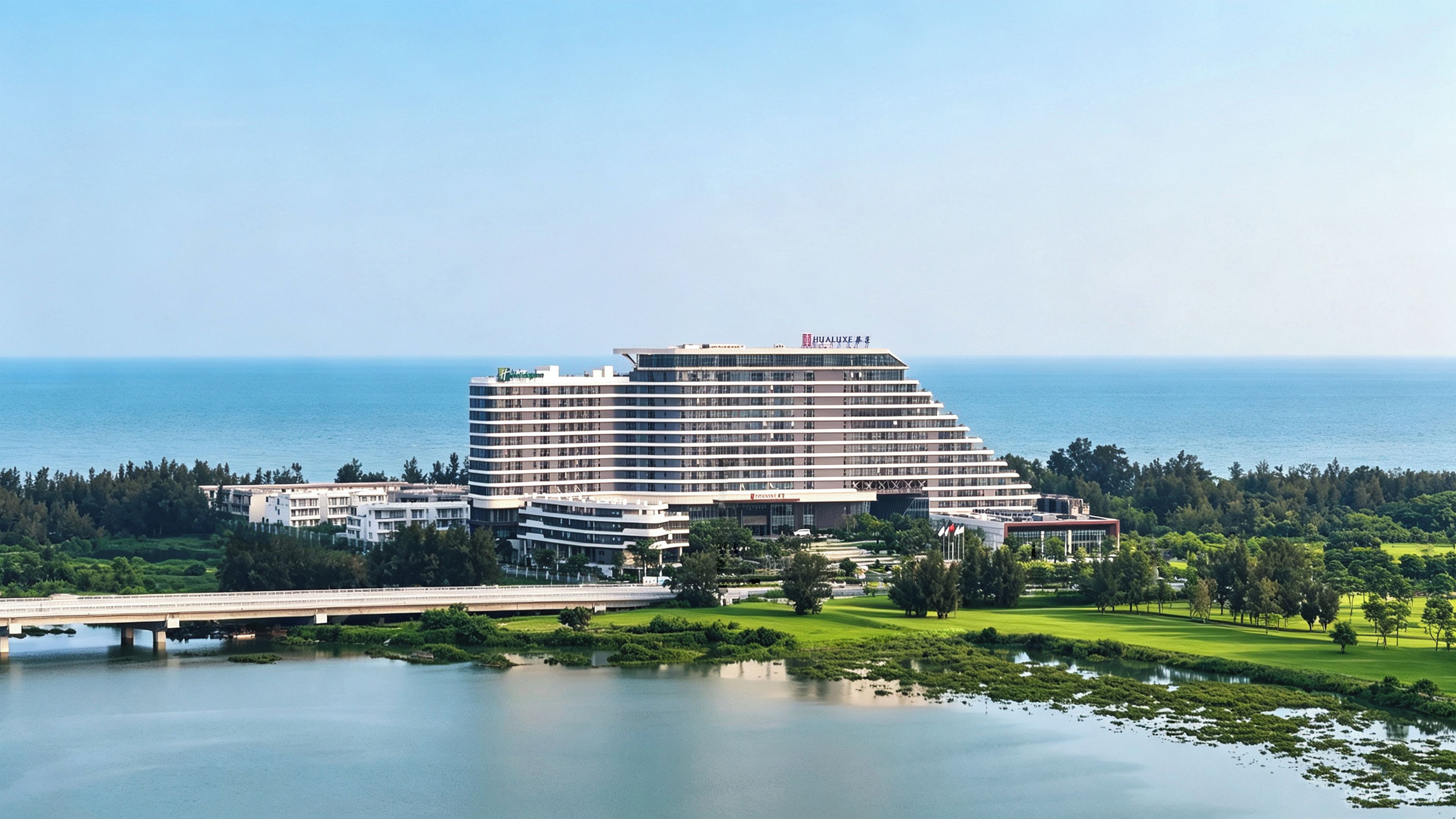 A large hotel with multiple floors and a view of the sea.