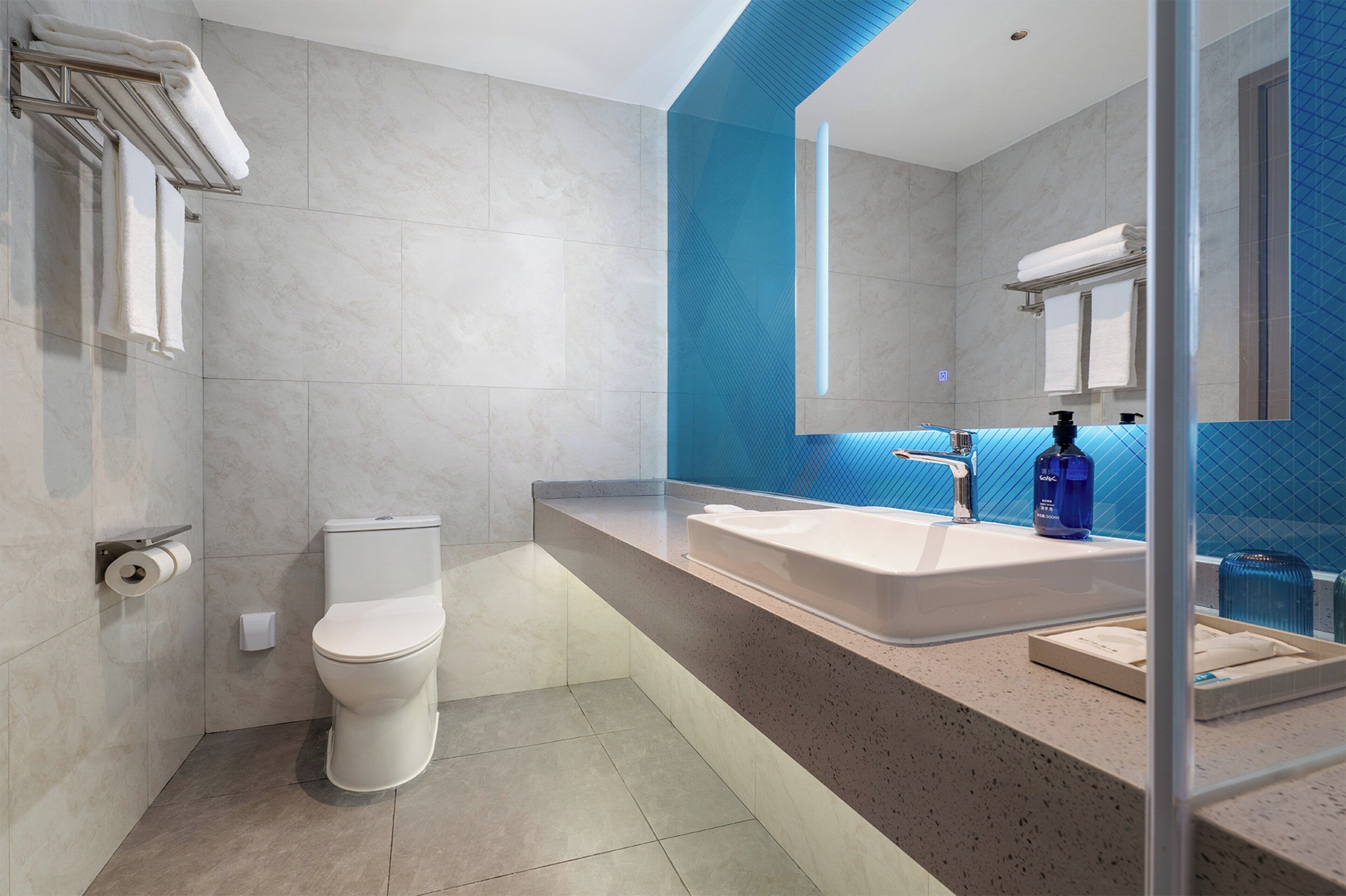 A modern bathroom with a white toilet, a large sink, and a mirror.