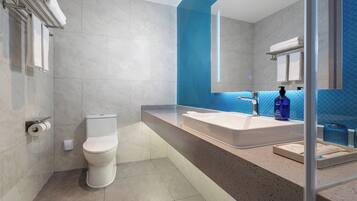 A modern bathroom with a white toilet, a large sink, and a mirror.