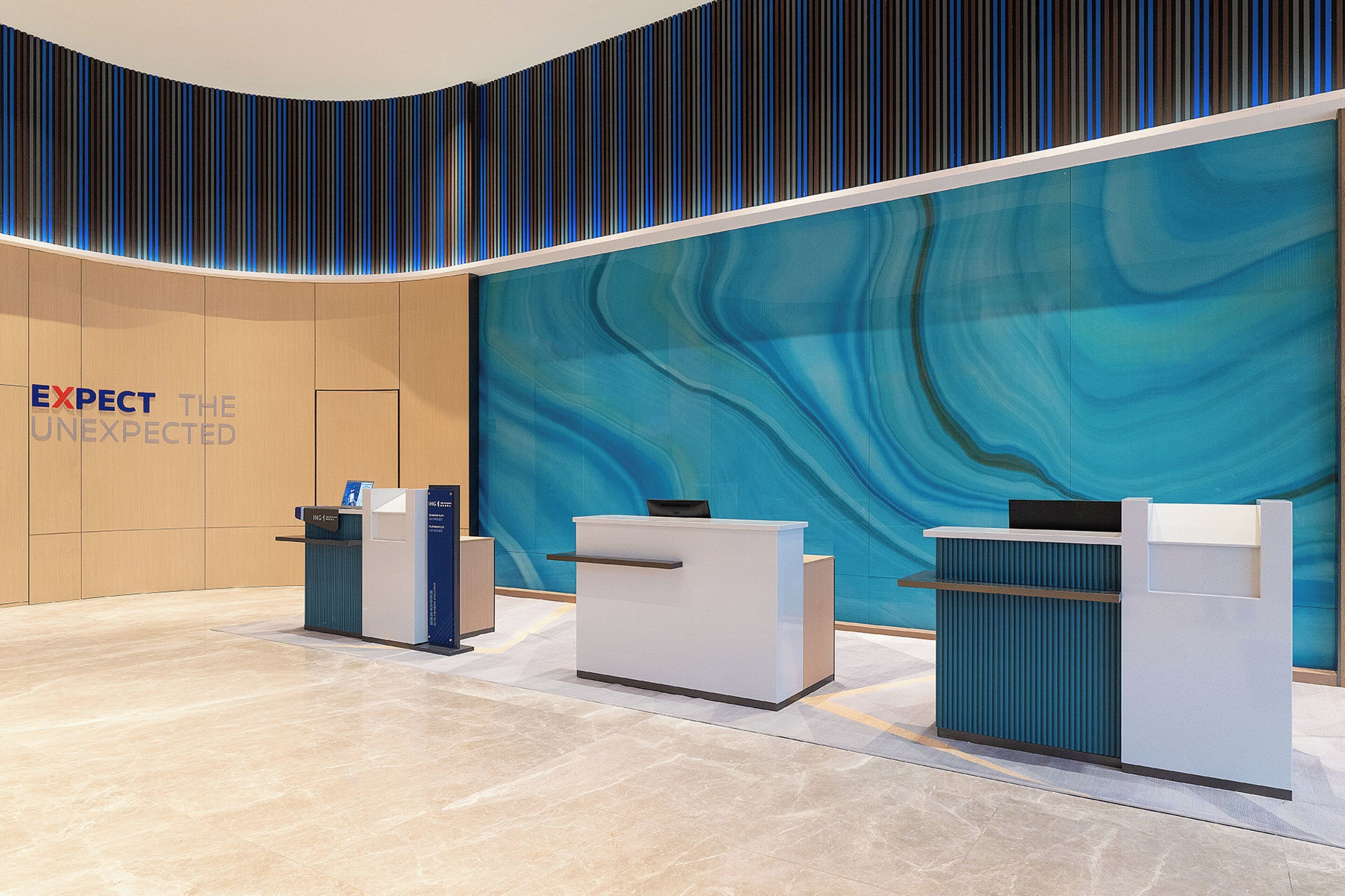 A reception area with a modern design, featuring a blue abstract wall, a reception desk, and a counter.