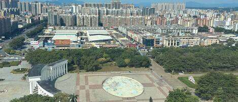 An urban landscape with high-rise buildings, a large open plaza, and surrounding greenery.