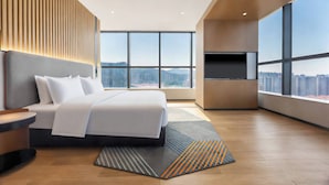 Une chambre d’hôtel moderne avec un grand lit, une télévision et une vue sur la ville.