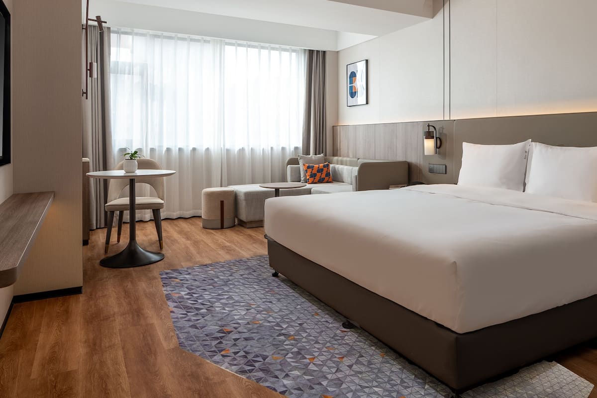 Une chambre d’hôtel moderne avec un grand lit, un petit bureau, une chaise et un canapé.