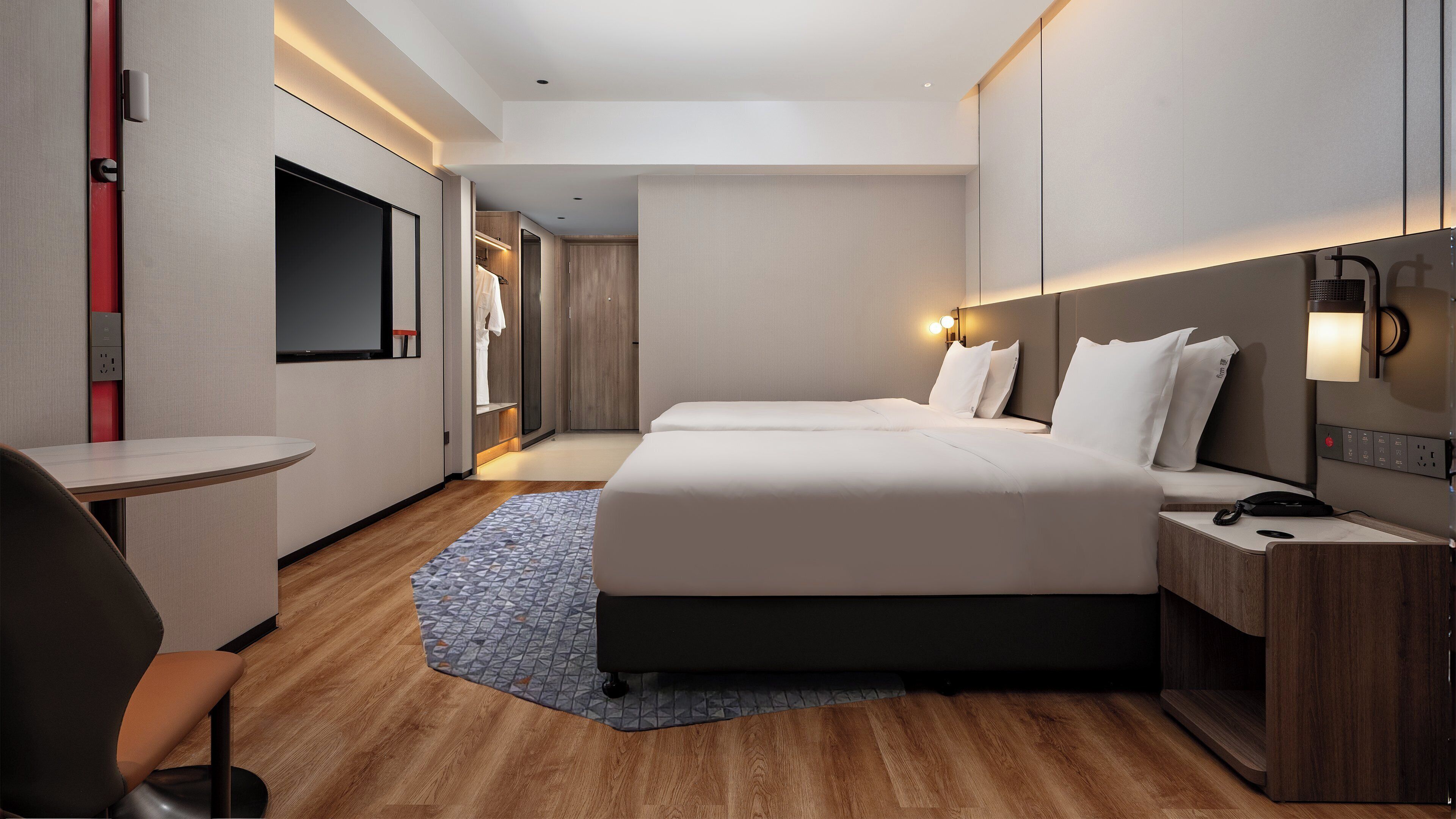 Una habitación de hotel moderna con una cama grande, mesitas de noche, un escritorio y una zona de ducha.