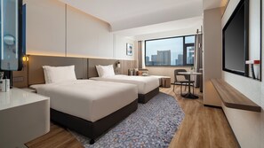 Een moderne hotelkamer met twee bedden, een tafeltje en een zithoek.