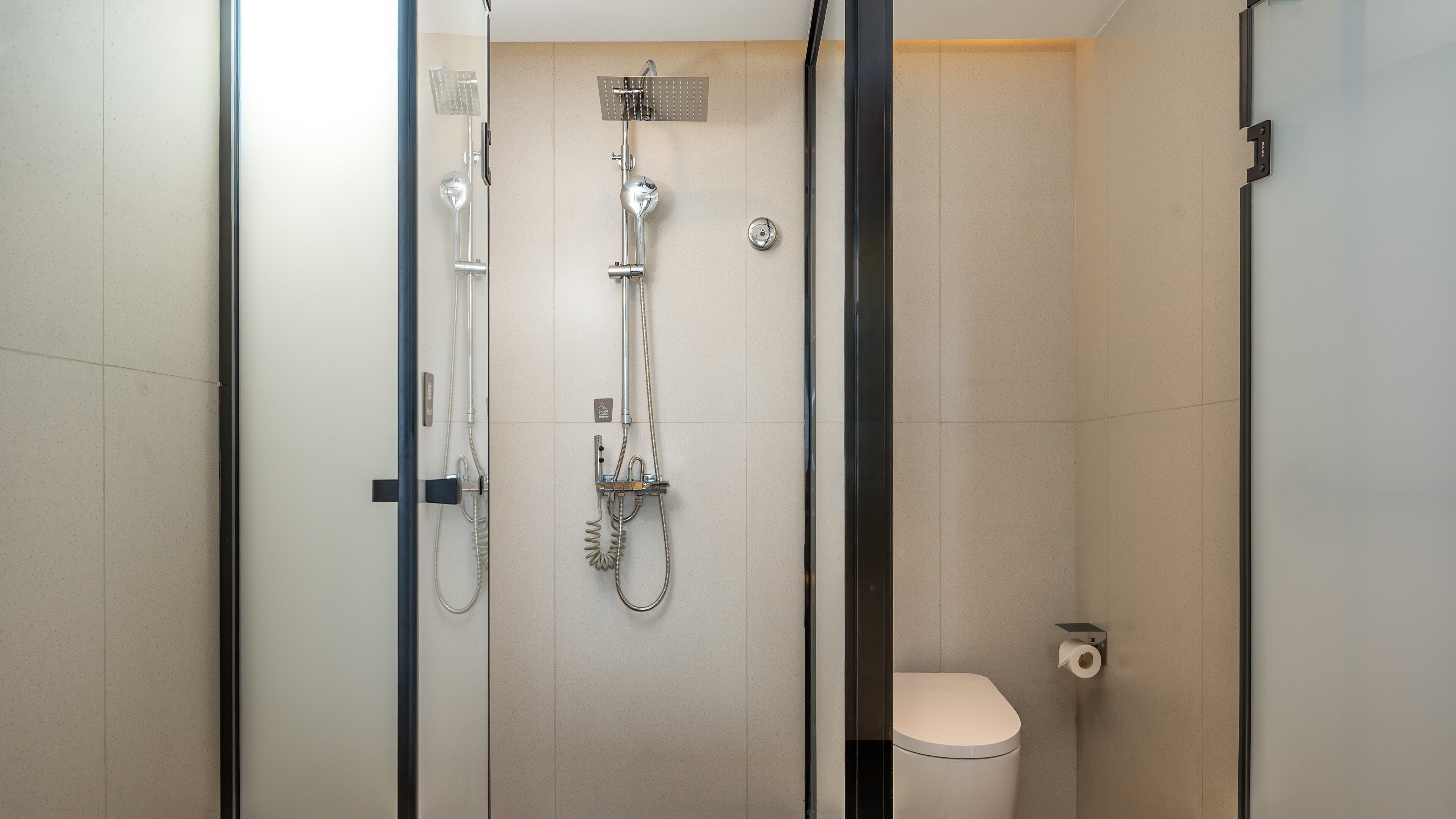 Ein modernes Badezimmer mit Duschkabine aus Glas, Toilette und Handtuchhalter.