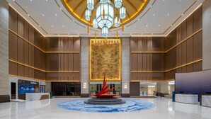 Un hall d’entrée spacieux avec une fontaine centrale, un comptoir d’accueil et un café.