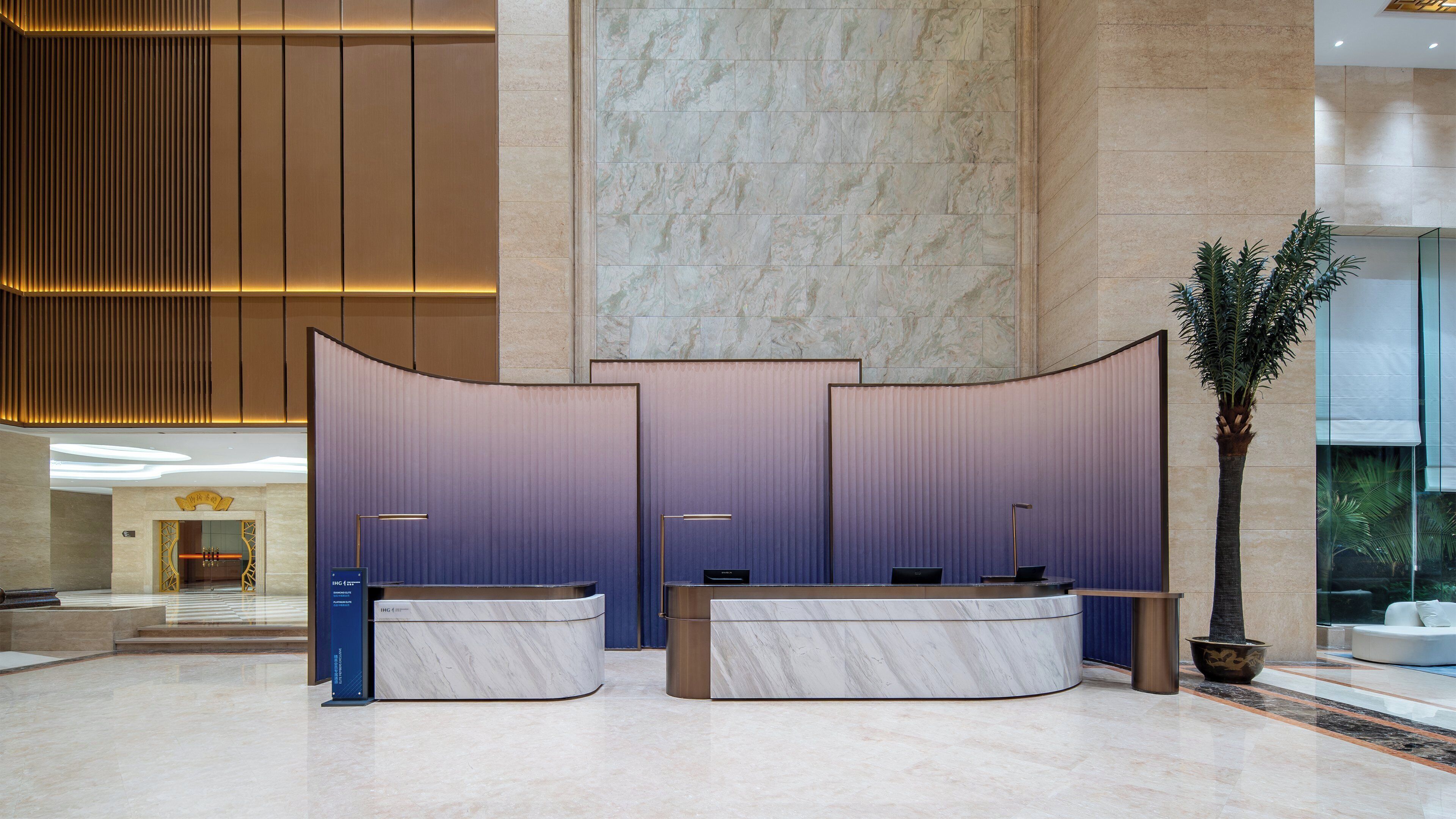 A reception area with a marble reception desk, a large potted plant, and a modern interior design.