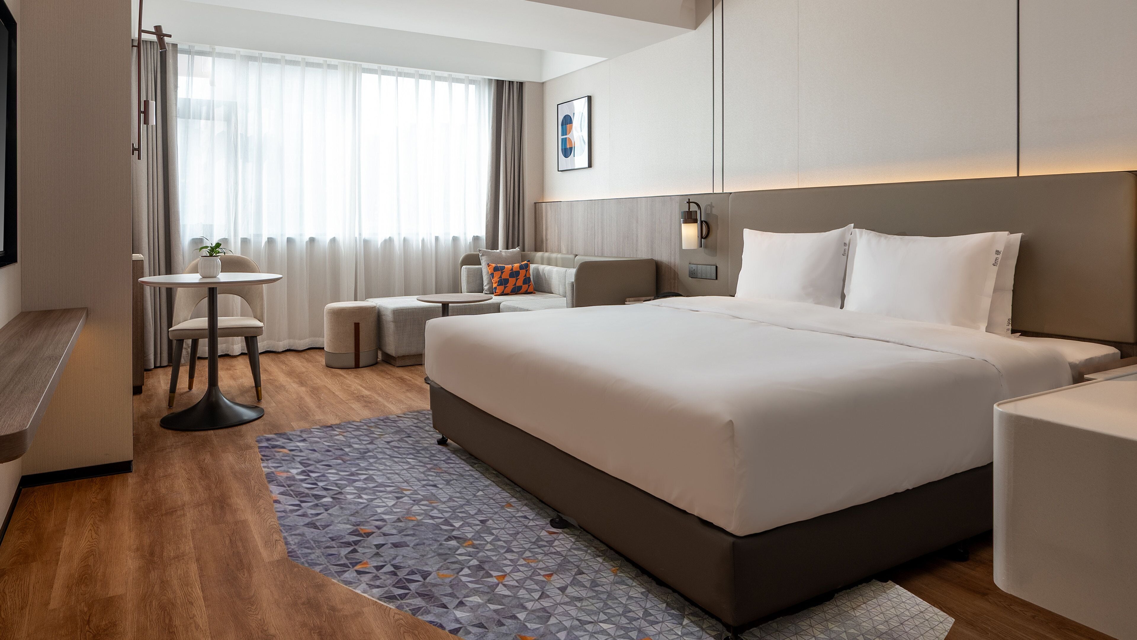 Una habitación de hotel moderna con una cama grande, un escritorio pequeño, una silla y un sofá.
