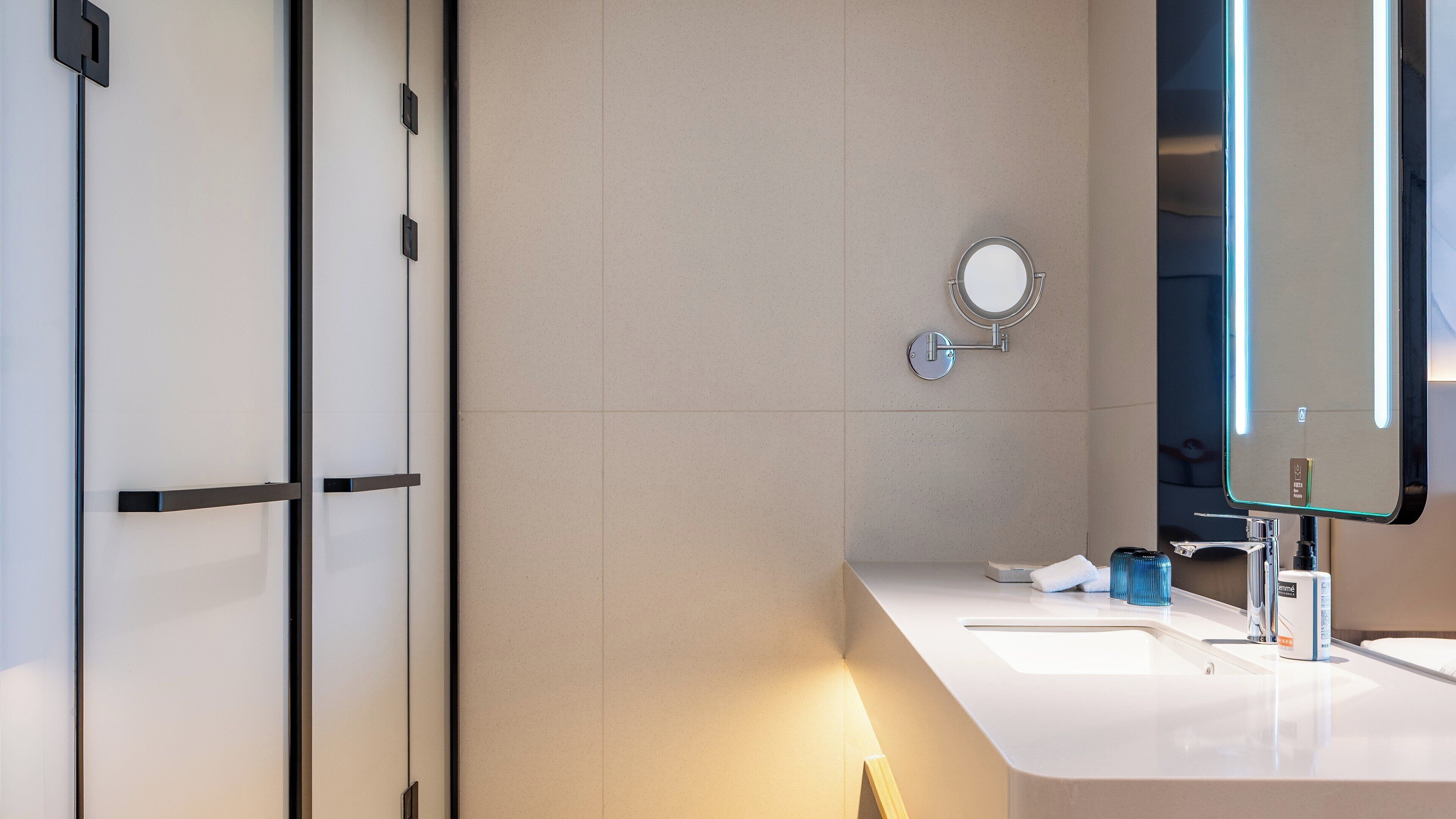 Un baño moderno con dos lavamanos, un espejo y un dispensador de toallas.
