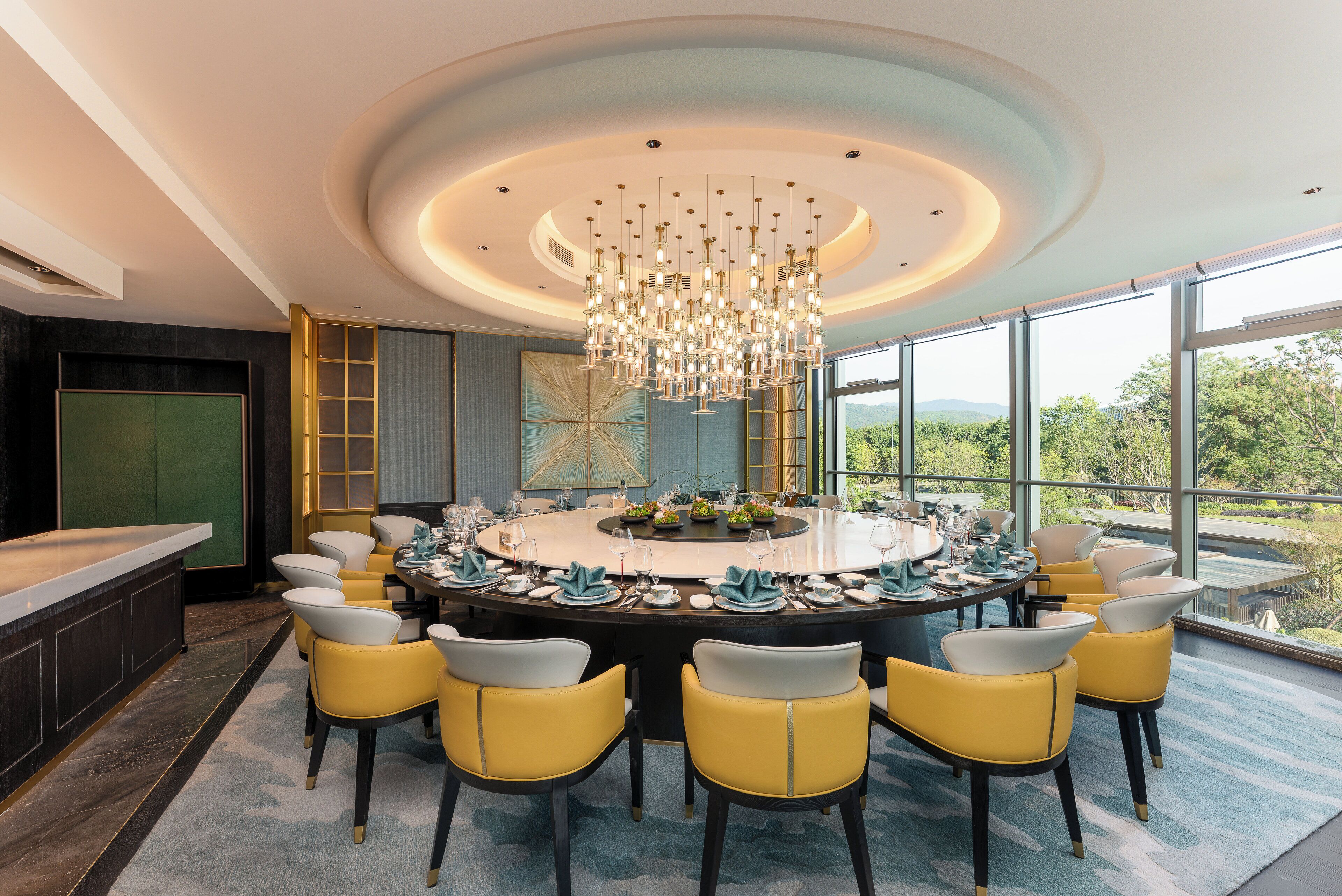 Un'elegante zona pranzo con un tavolo rotondo, sedie gialle e un lampadario.