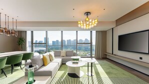 Una sala de estar moderna con un ventanal grande, un televisor de pantalla plana, un sofá, una mesa de centro y un comedor con sillas.