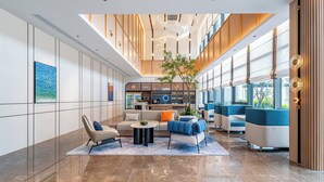 A spacious lobby with a high ceiling, seating areas, a coffee shop, and large windows. - Holiday Inn Express Taizhou Jiaojiang by IHG (Taizhou)