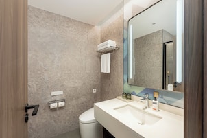 Un baño moderno con pared de mármol, un lavamanos blanco, un espejo grande y un perchero para toallas.