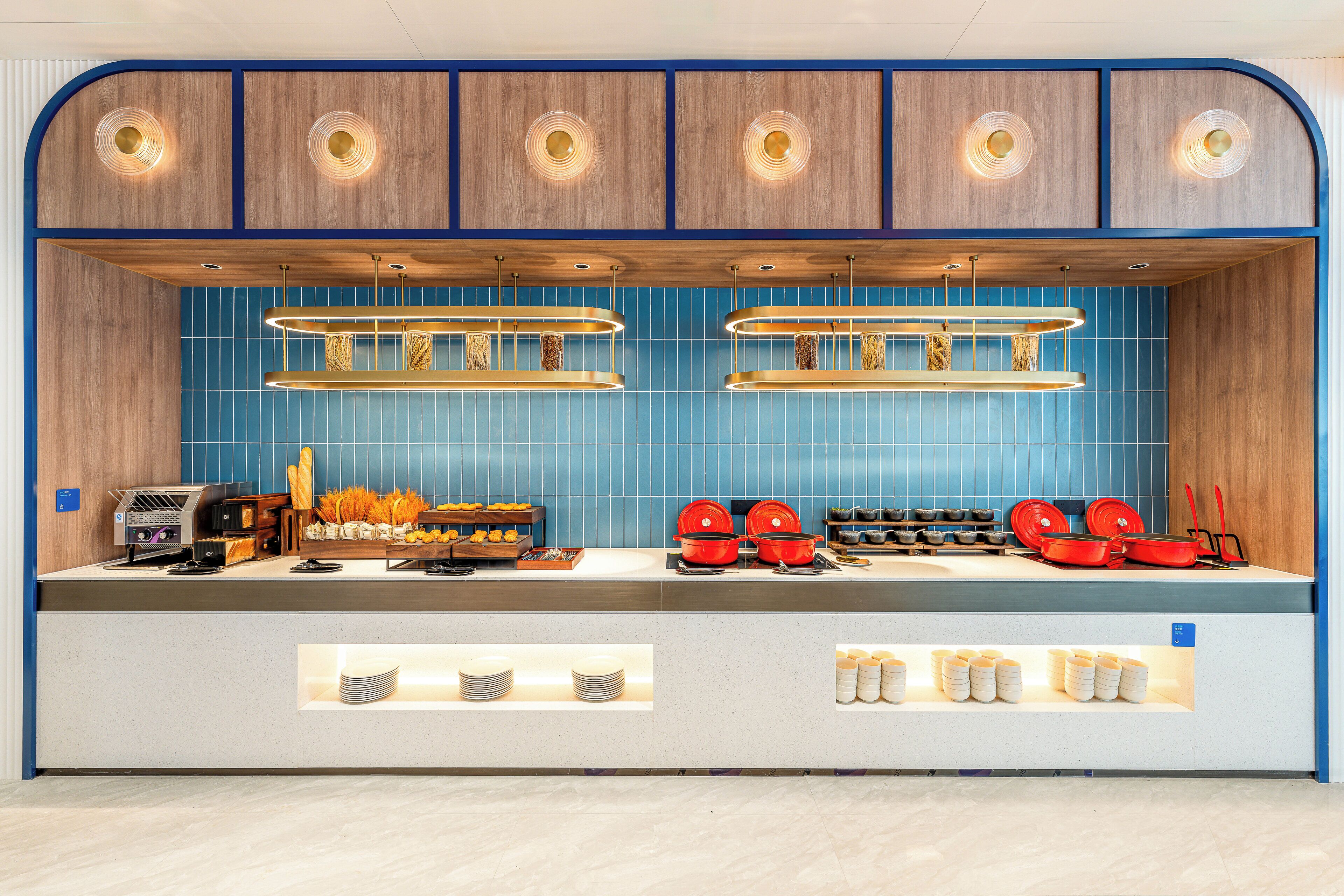 A modern kitchen with blue tiles, wooden cabinets, and a coffee station.