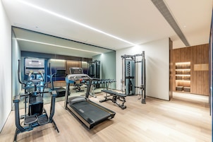 Un gimnasio moderno con máquinas de cardio, pesas libres y un espejo grande.