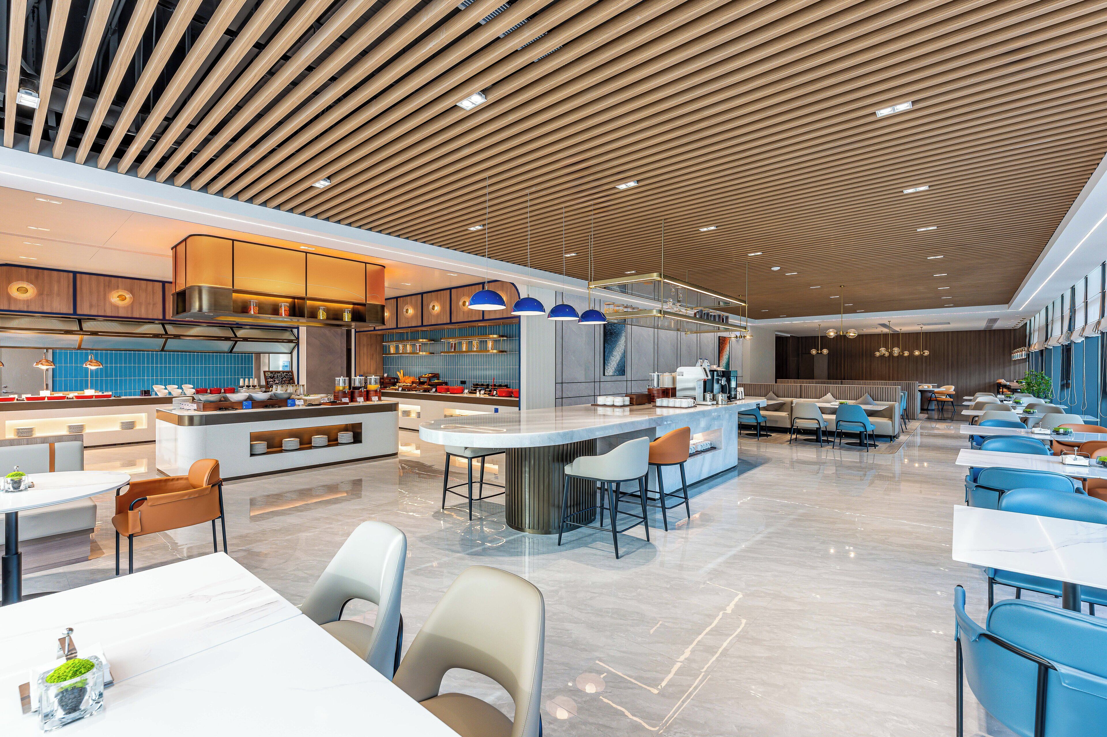 Un restaurante moderno con una isla central, zonas de estar y techo de madera.