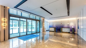 A modern hotel lobby with a glass entrance, a reception desk, and a blue carpet. - Holiday Inn Express Taizhou Jiaojiang by IHG (Taizhou)