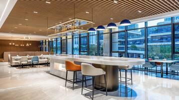A modern bar area with a curved counter, two bar stools, and a seating area with a sofa and chairs.