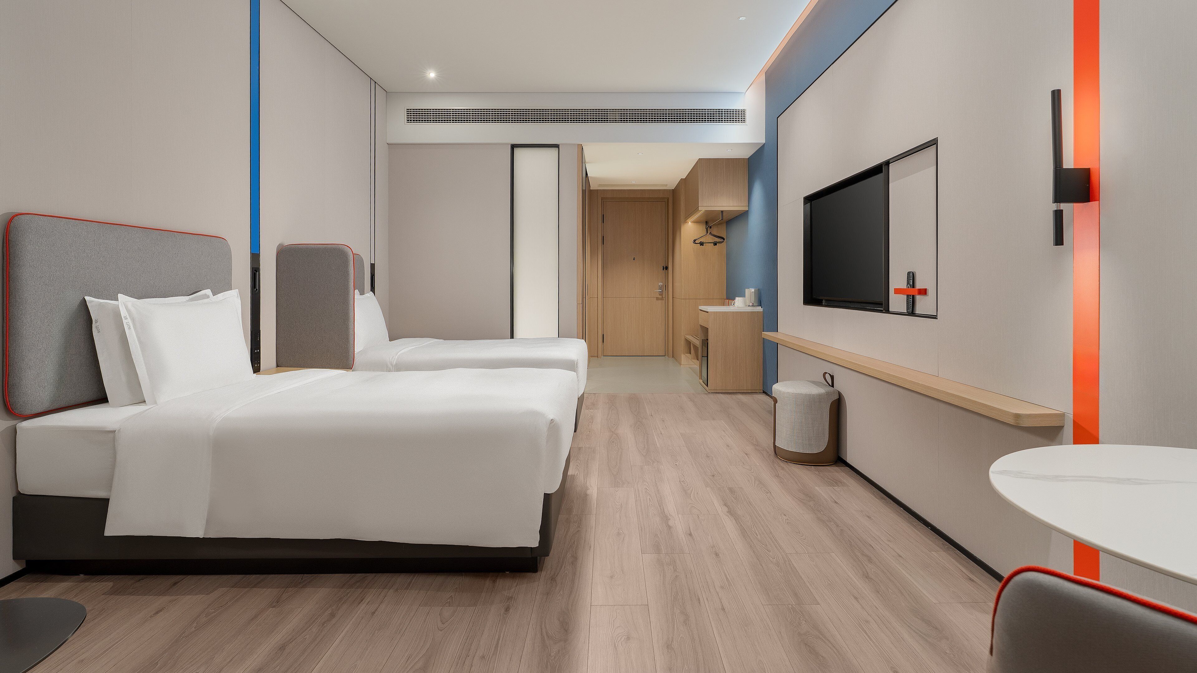 Een hotelkamer met twee bedden, een televisie, een klein tafeltje en een badkamer die door een open deur zichtbaar is.