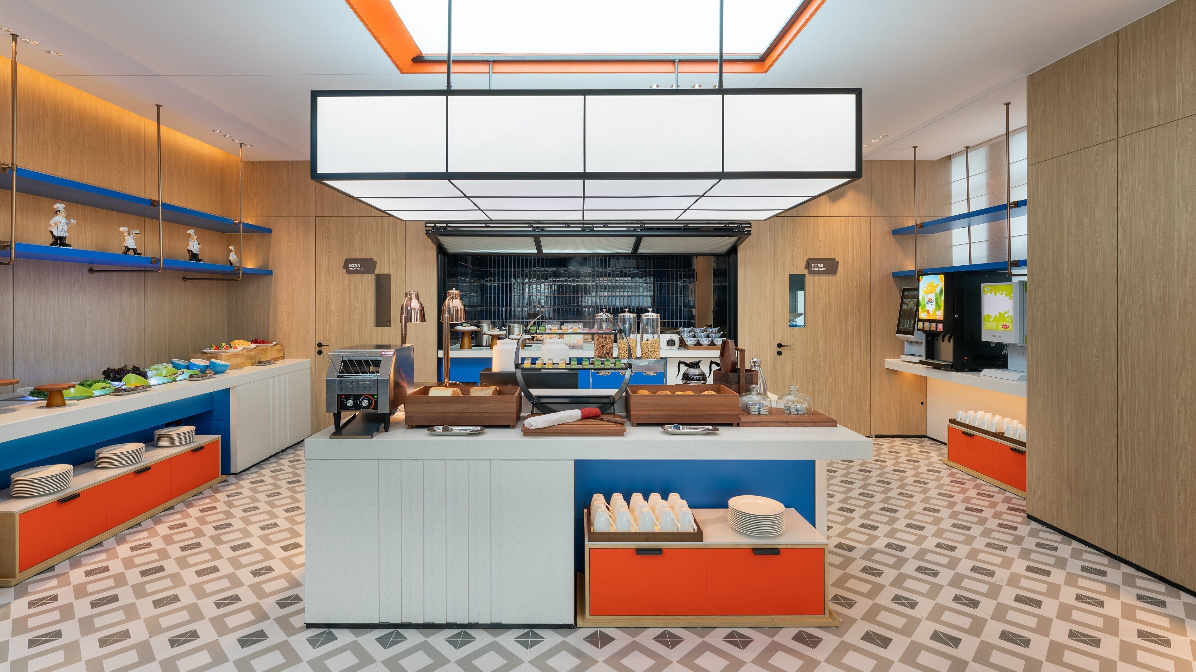 Ein moderner Frühstücksbereich mit einem zentralen Buffet, einer Kaffeemaschine und einer Selbstbedienungs-Getränkeausgabe.