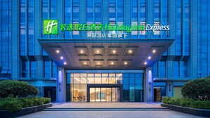 A hotel entrance with a modern facade, large glass doors, and a sign indicating it is part of the Holiday Inn Express chain. - Holiday Inn Express Quanzhou Fuqiao by IHG (Quanzhou)