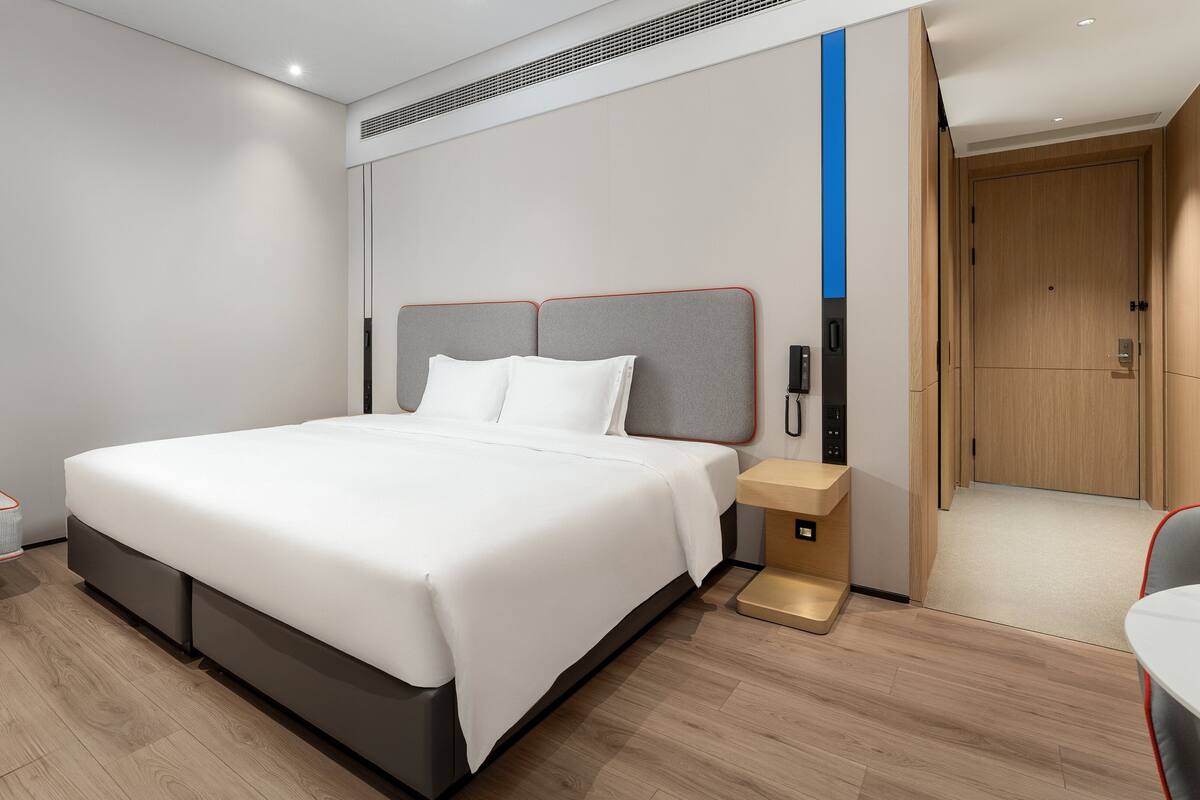 Une chambre d’hôtel moderne avec un grand lit, une table de chevet, une chaise et un bureau.