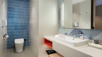 A bathroom with a white sink, a mirror, and a blue-tiled wall.