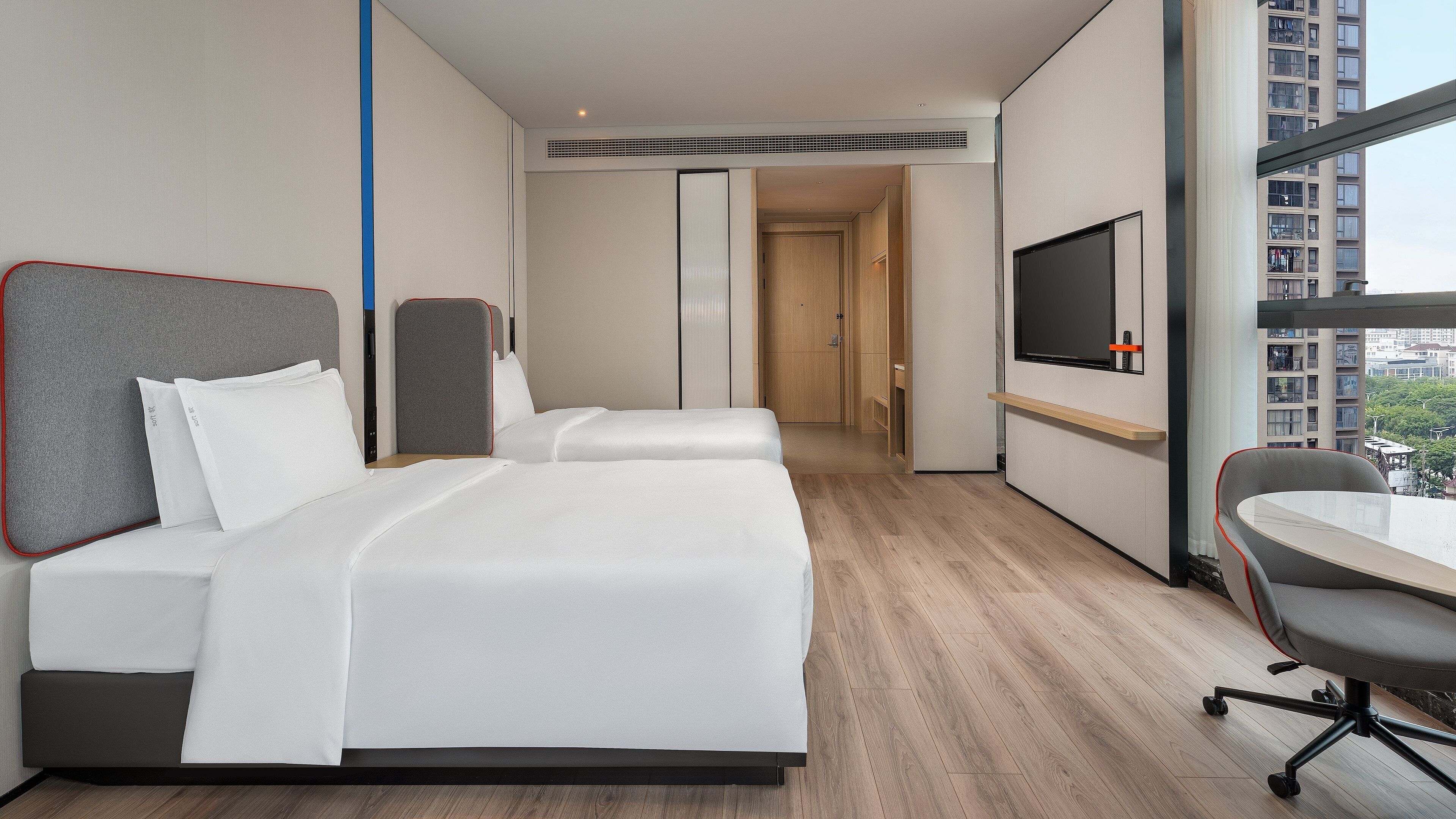 A hotel room with two beds, a TV, a desk, and a chair.
