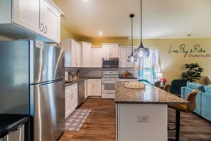 A modern kitchen with stainless steel appliances, white cabinetry, and a granite countertop.