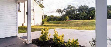 A house with a covered porch, a well-maintained lawn, and a welcome mat.