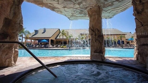 Un jacuzzi con vista a una piscina y un edificio con techo de tejas.