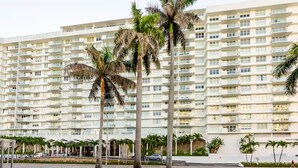 A multi-story hotel with a uniform facade, balconies, and palm trees in the foreground. - Beach Oasis w/ Balcony, Pool, Gym - Elevator to Beach (Miami Beach)