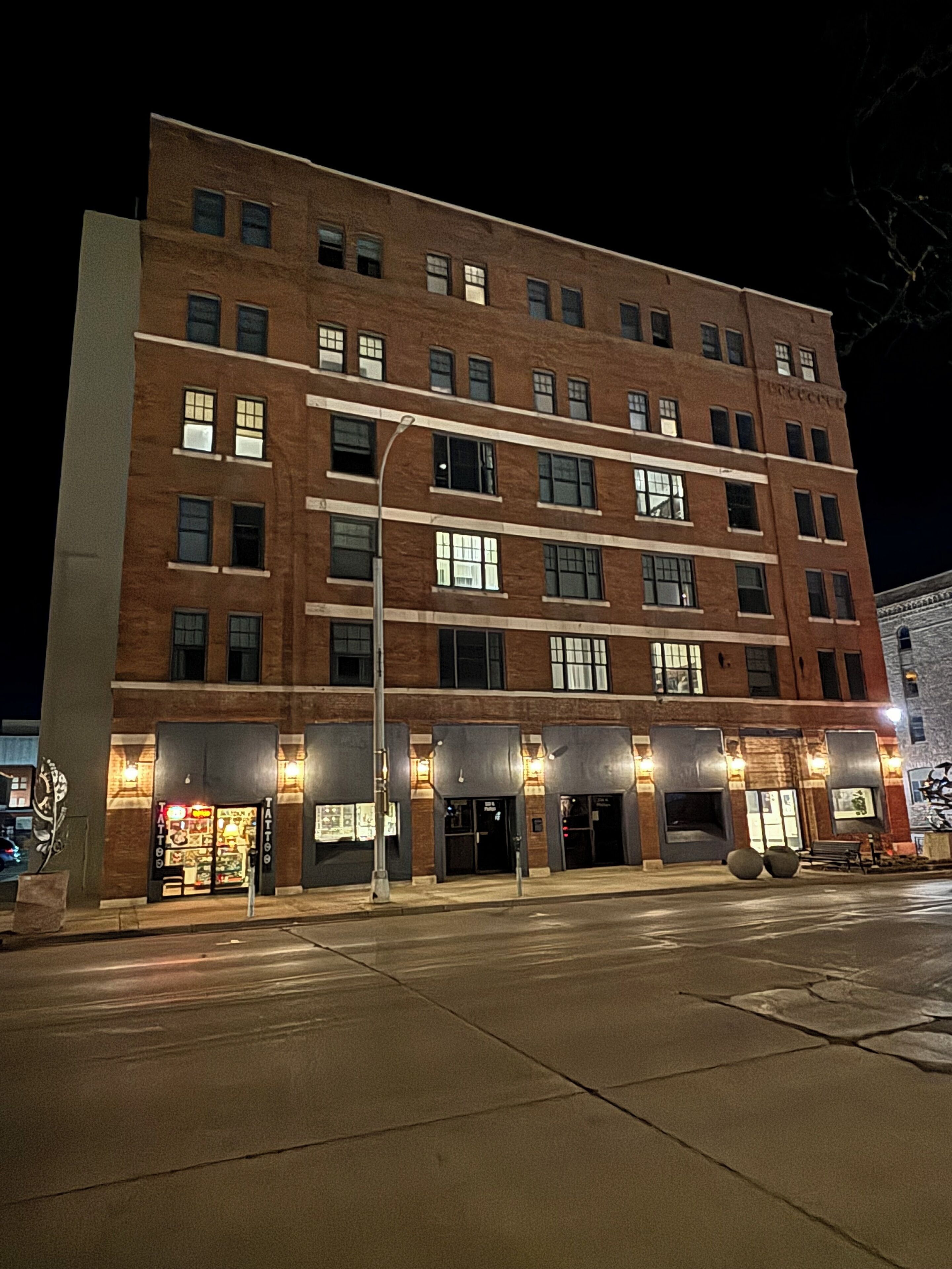 Un hôtel à plusieurs étages, doté d’une façade en briques, de nombreuses fenêtres et d’enseignes lumineuses.