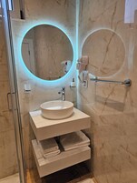 Un baño moderno con un espejo redondo, un lavabo y un perchero para toallas.