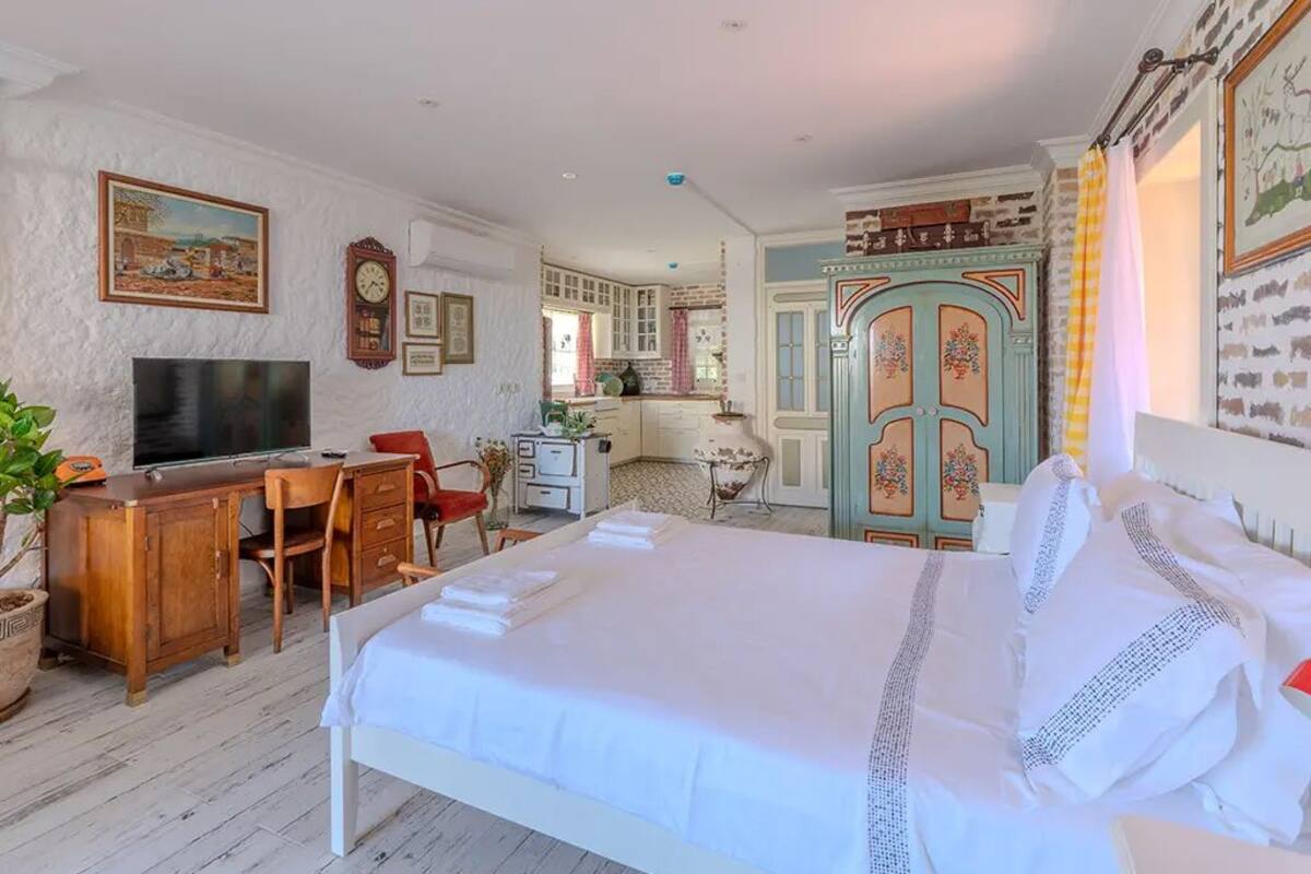 Une chambre à coucher avec un lit, un bureau, une télévision et une chaise.