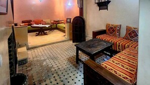 A cozy living room with a patterned floor, a sofa set, a coffee table, and a decorative archway.